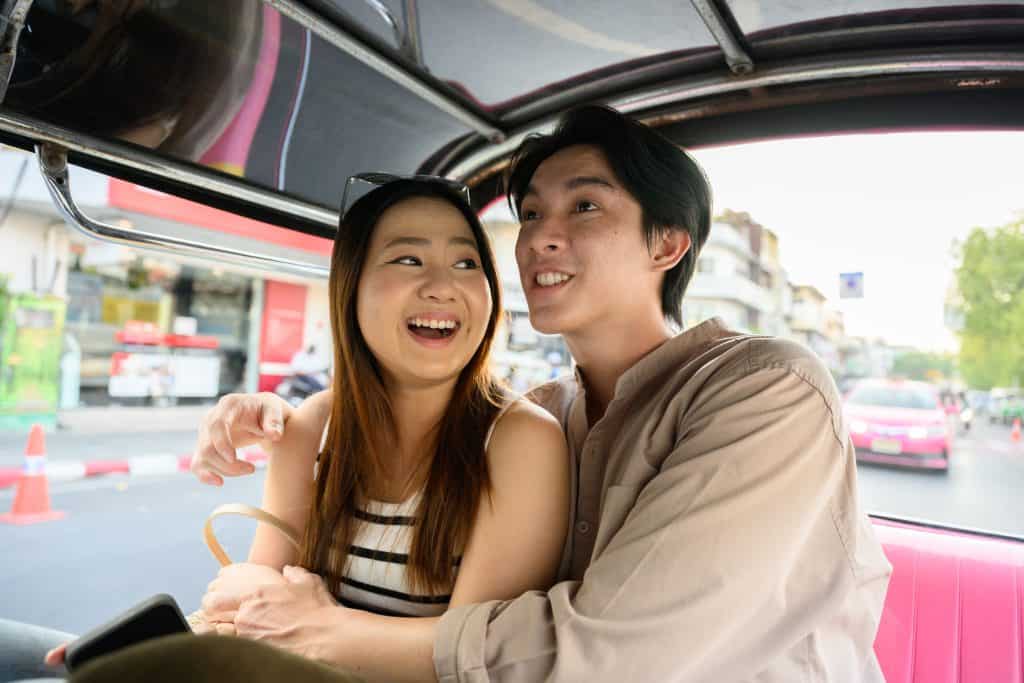 Young couple in casual clothes laughing and enjoying a tuk-tuk ride through the bustling streets of bangkok, experiencing the vibrant culture and sights of Thailand. travel concept. Thai Phrases for Dating