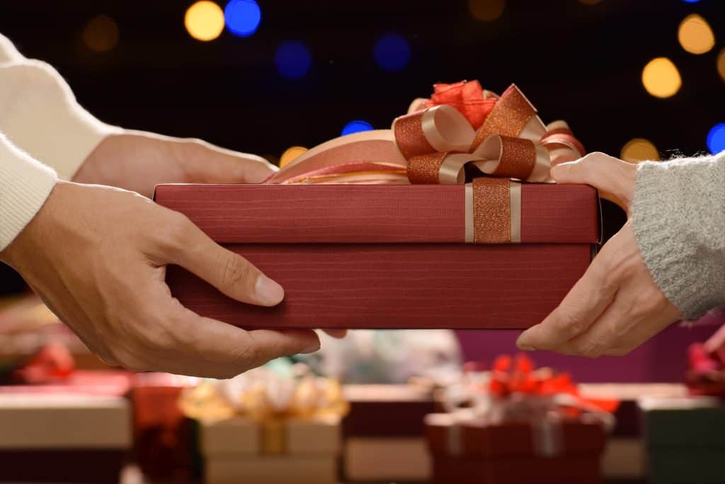 People giving presents to one another in Christmas and New year Festivals with boxes of presents in the background
